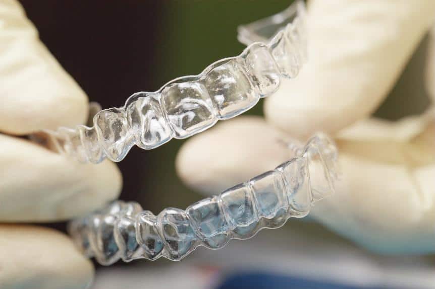Two clear orthodontic aligners held up to light, showing transparent dental treatment trays.