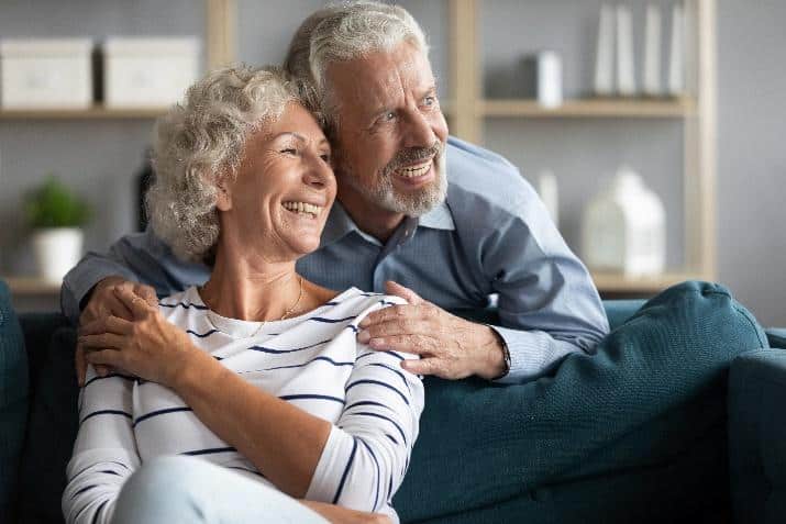 Mature couple smiling while relaxing together on a couch at home.