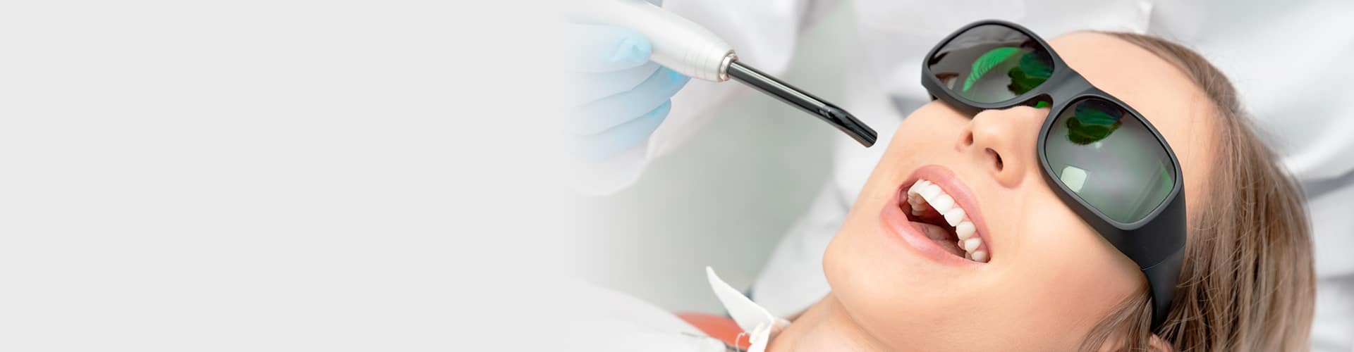 Patient receiving dental treatment wearing protective eyewear in modern dental office setting