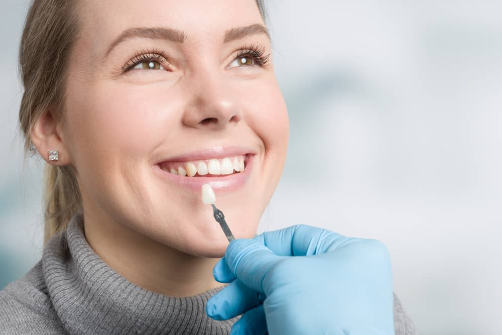 Dentist in blue gloves examining patient's teeth during dental checkup in clinical setting.
