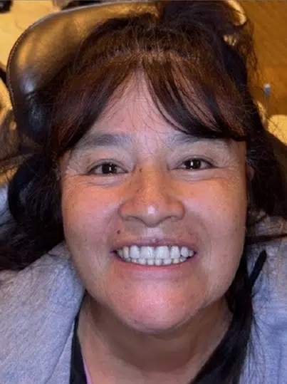 Person smiling at camera wearing headphones, indoor setting with warm lighting.