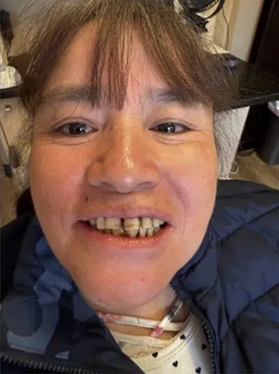 Smiling person in dark jacket indoors, displaying friendly expression for dental practice website.