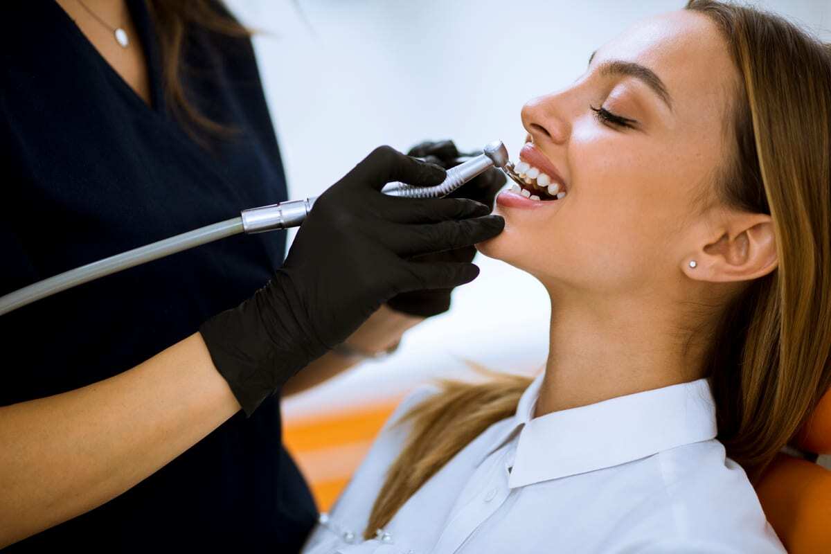 Dentist in black gloves examining patient's teeth during dental procedure.